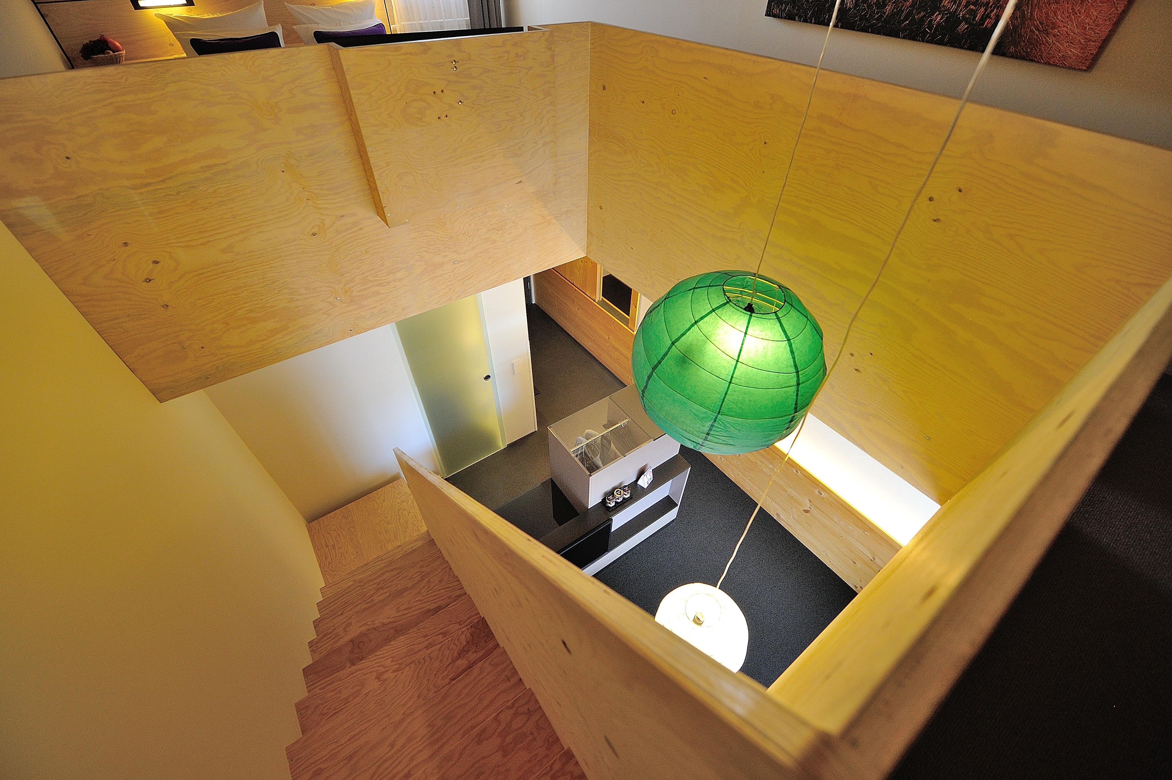 Une pièce dotée d’une structure en bois, un objet sphérique vert suspendu au plafond et une petite table sur laquelle se trouvent divers objets.