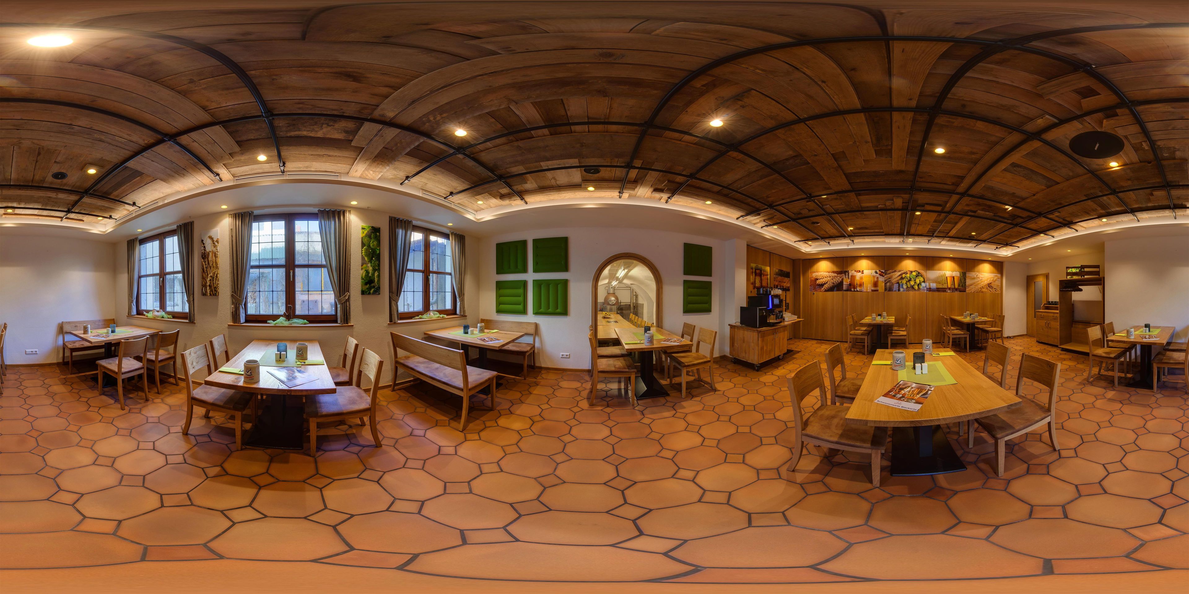 A spacious dining area with hexagonal patterned flooring, wooden tables and chairs, and a high, arched ceiling with exposed beams.