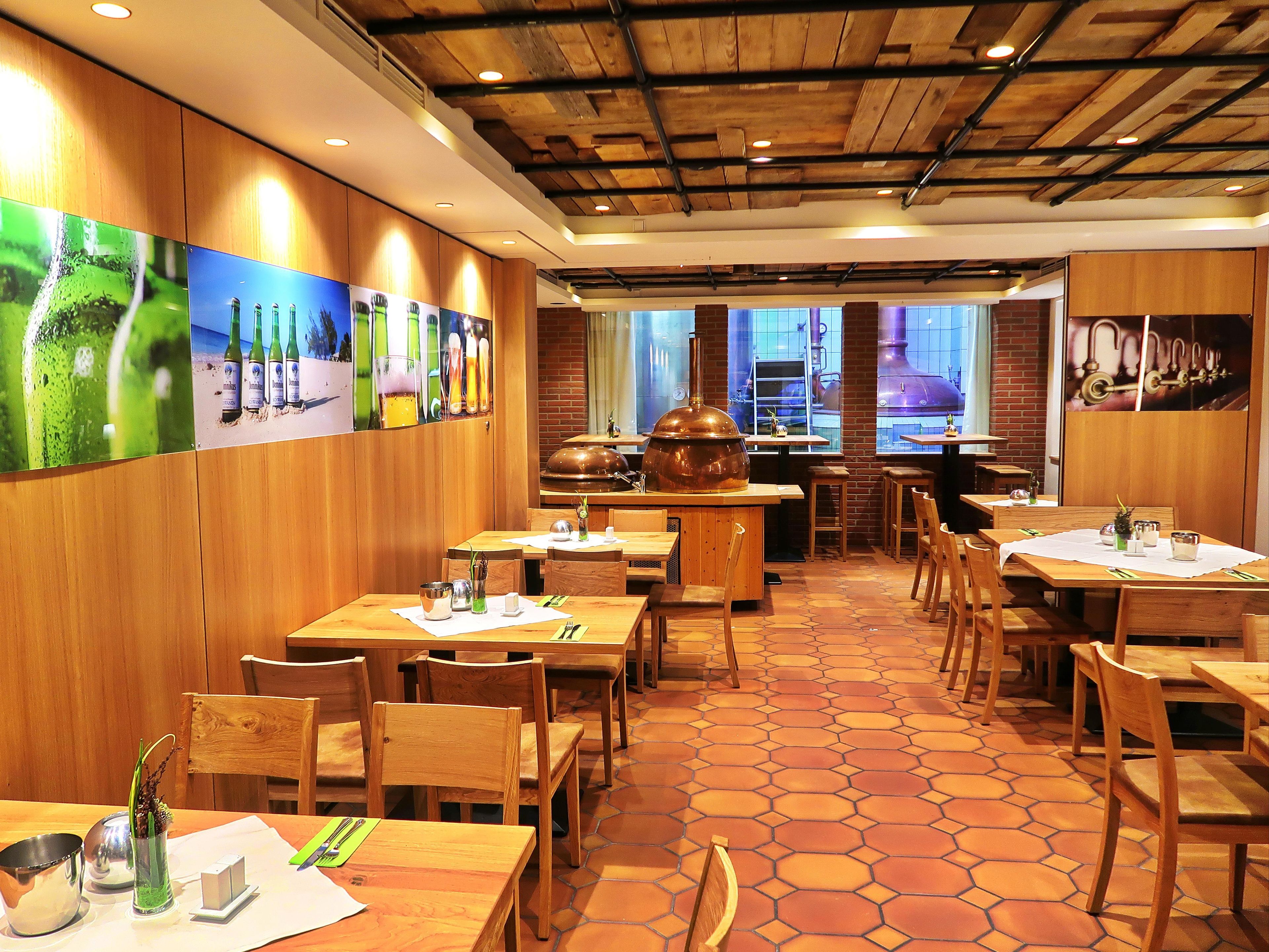 A restaurant interior with wooden tables and chairs, a tiled floor, and a brick wall.