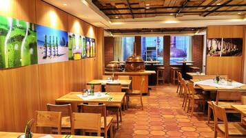 A restaurant interior with wooden tables and chairs, a tiled floor, and a brick wall.