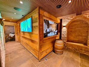 Un intérieur en bois avec un mur en pierre, un tonneau en bois et un écran de télévision.