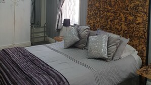 A bedroom with a bed, a dresser, a mirror, and a window with curtains. - Waters Edge (Blackpool)