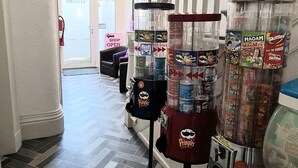A hallway with a 'SHOP OPEN' sign, vending machines, and a 'Welcome' door. - Waters Edge (Blackpool)