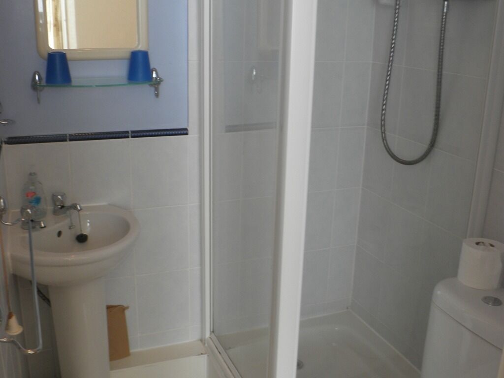 Une salle de bain équipée d’un lavabo, d’un miroir, d’une douche et de toilettes.