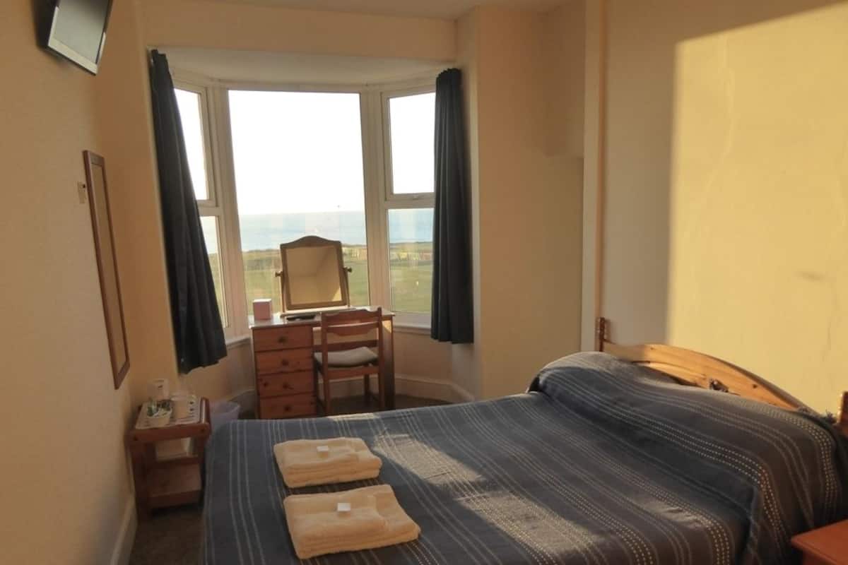 Un dormitorio con cama, una silla, cómoda y ventana con vistas.
