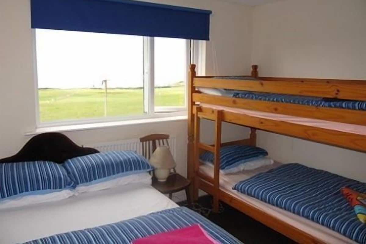 Habitación con literas, una ventana y vista a un campo verde.