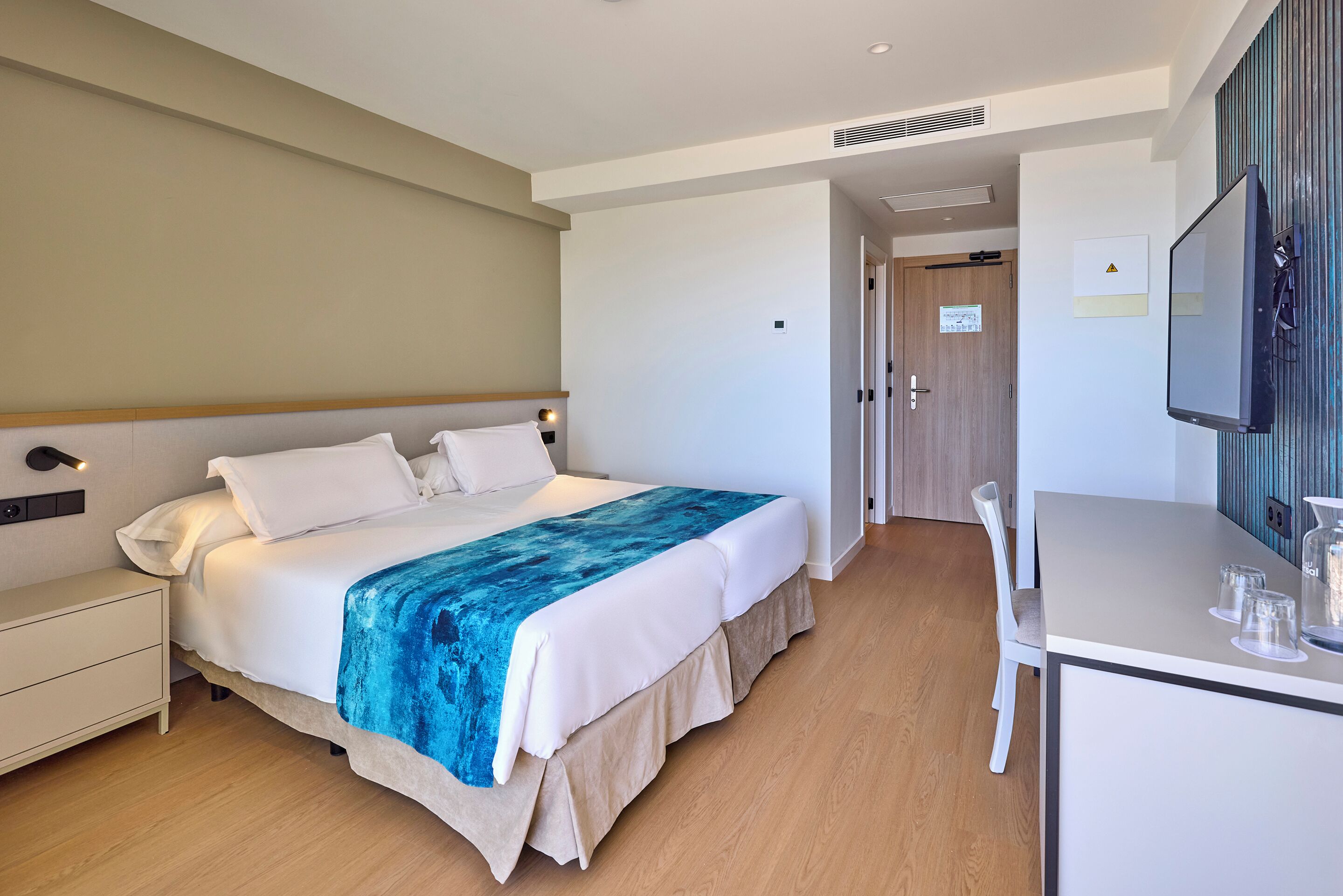Una habitación de hotel con cama, mesita de noche y escritorio con silla.