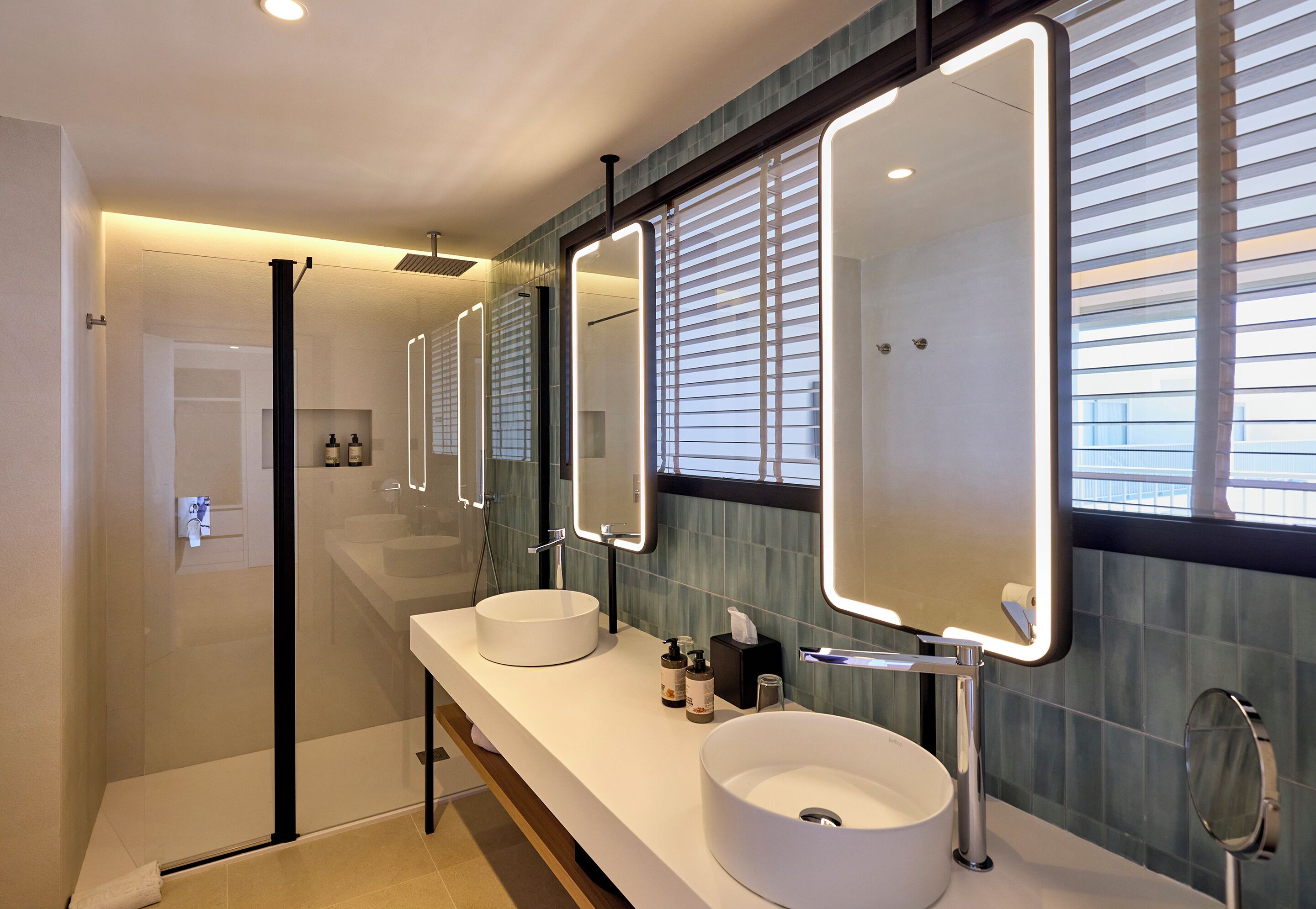 Un baño moderno con dos lavamanos, un espejo grande y una zona de ducha.