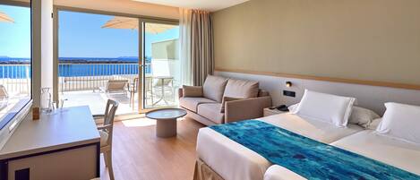 Habitación de hotel con balcón, cama, sofá, escritorio y una silla.