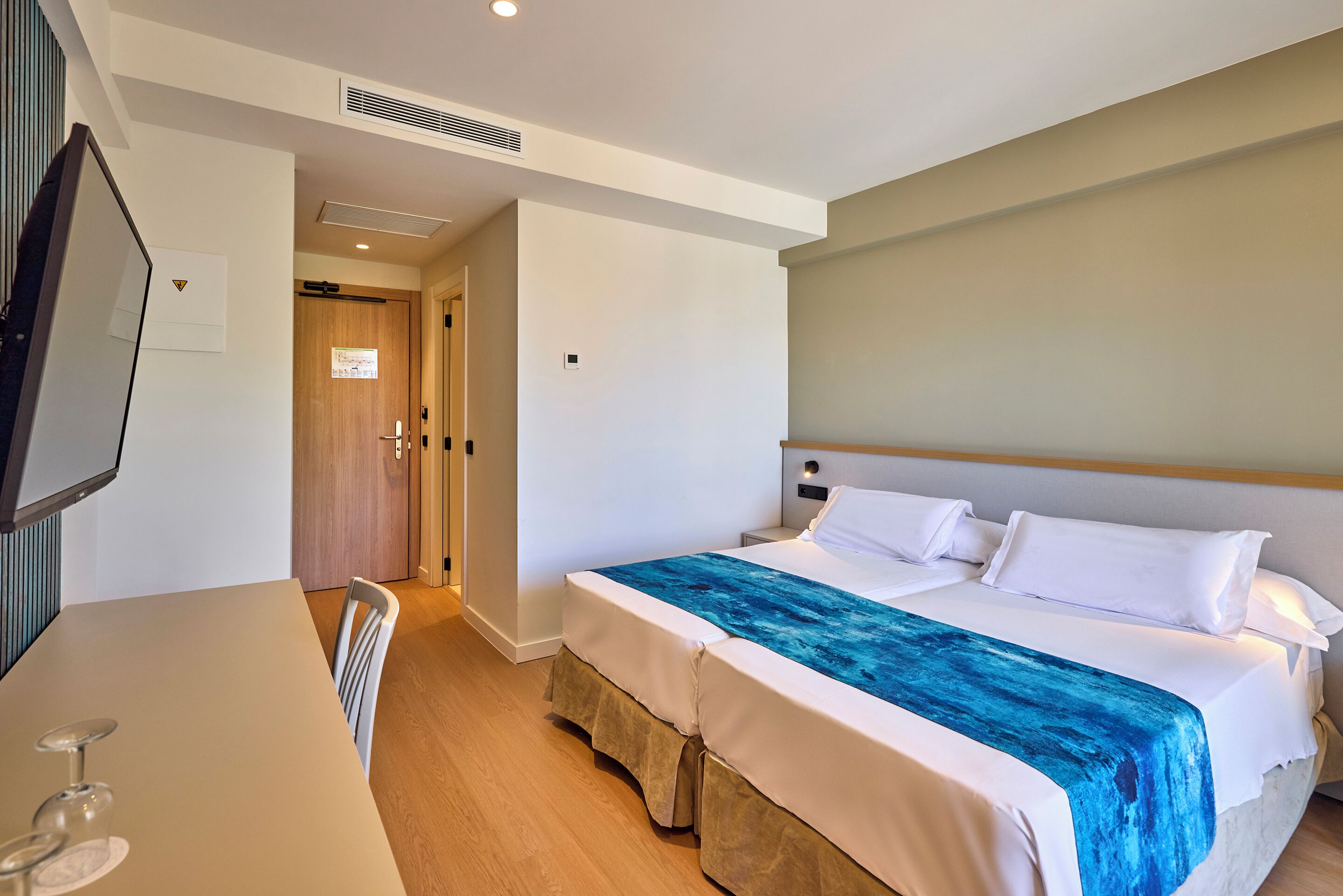 A hotel room with a bed, a desk, and a television.