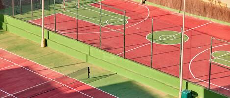 A tennis court with multiple courts, a net, and a fence.