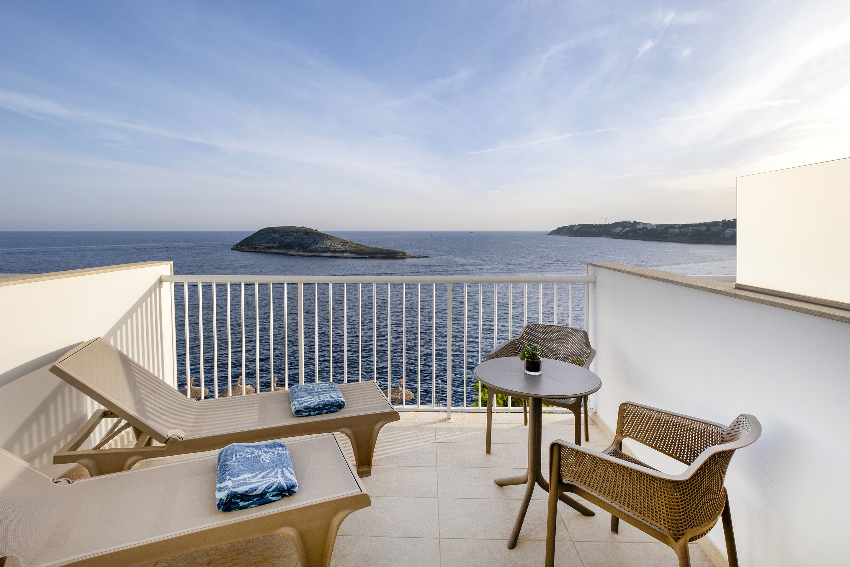 Un balcon avec vue sur la mer, une table et deux chaises.