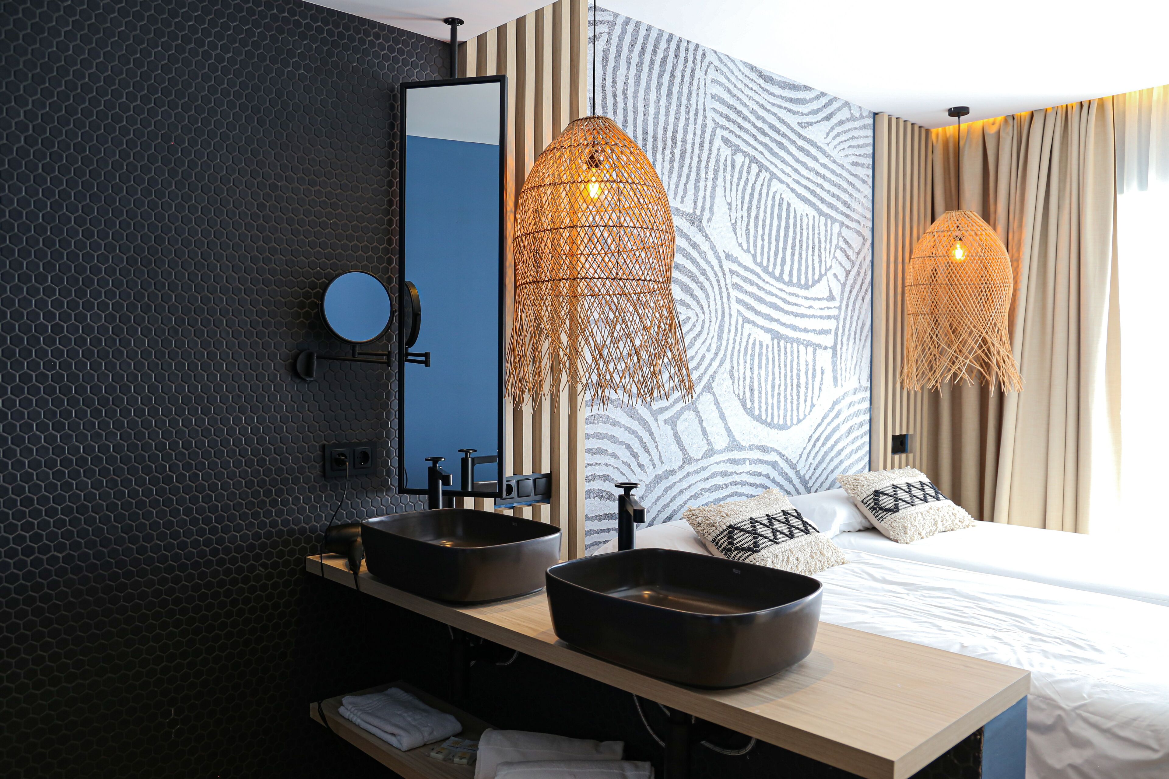 Um banheiro moderno com duas pias, um espelho e uma cama com cortinas estampadas.