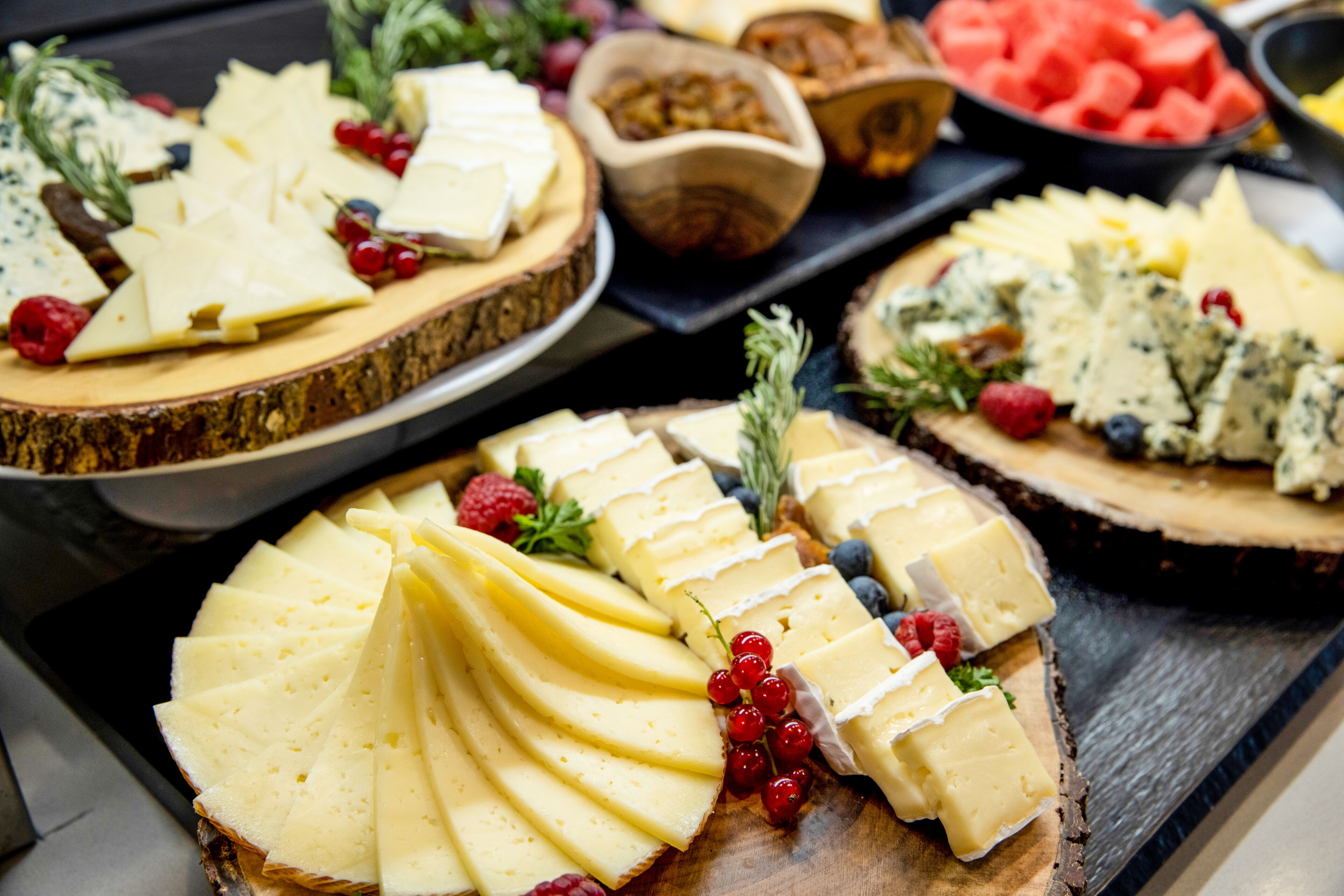 A variety of cheeses and fruits on wooden boards.