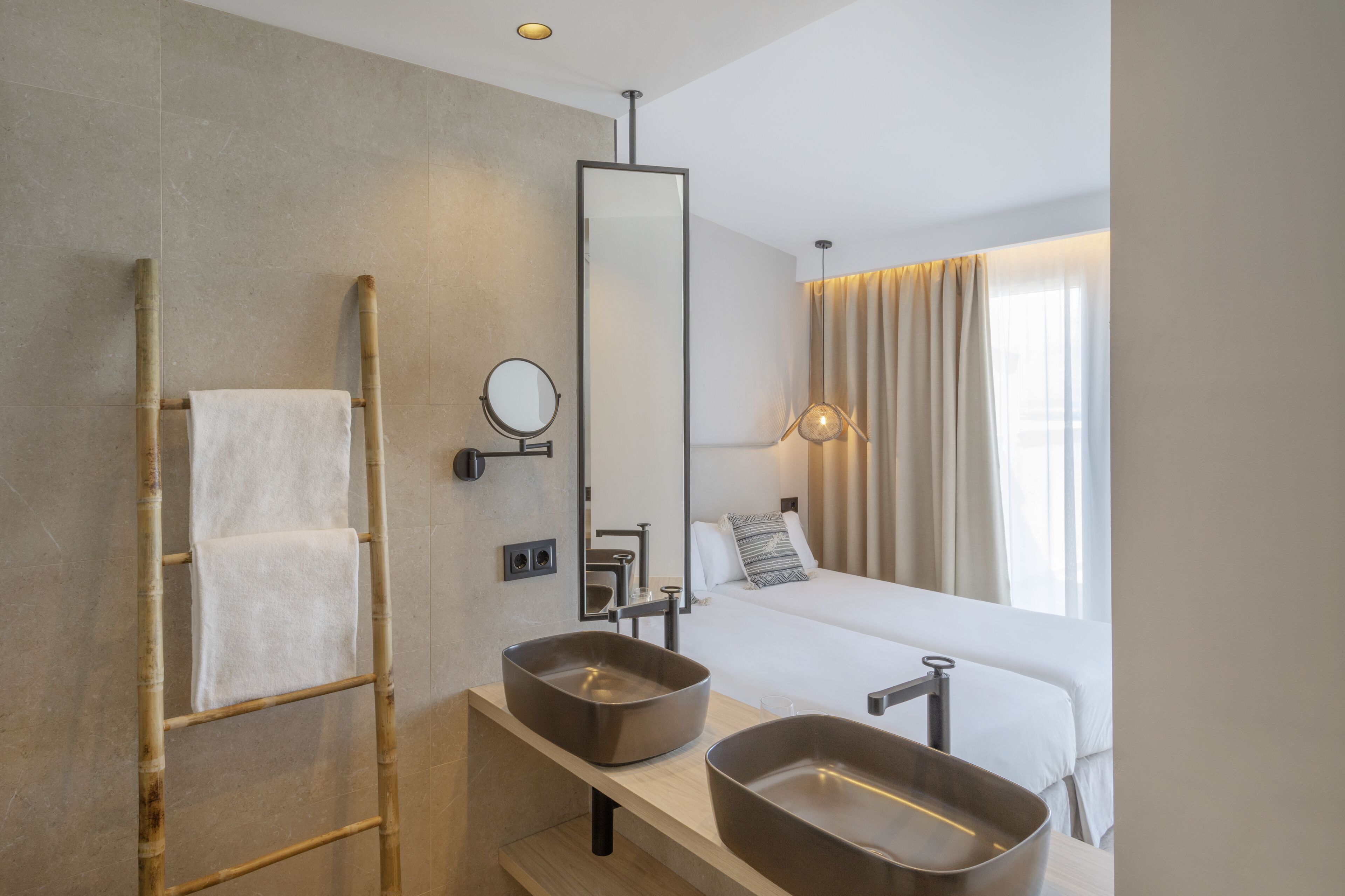 A modern bathroom with a large mirror, two sinks, and a towel rack.