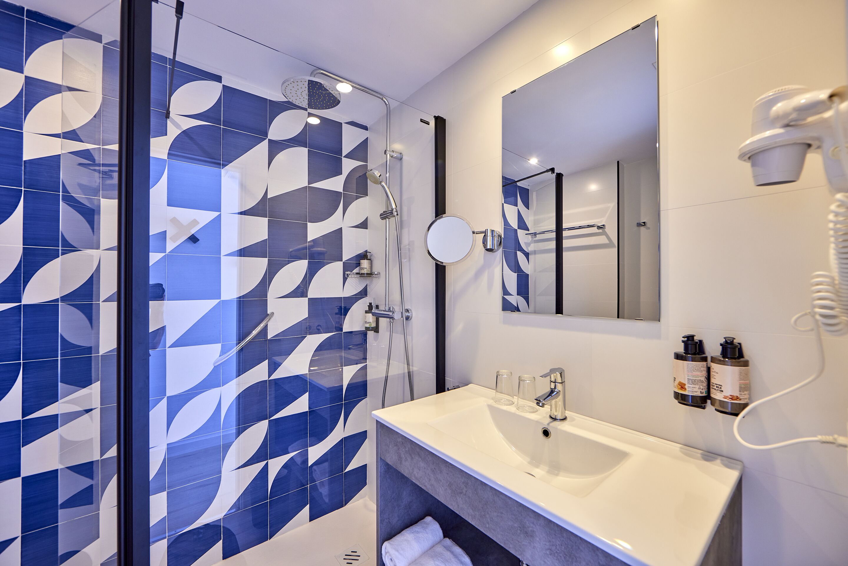 Un baño moderno con ducha, lavamanos y espejo.