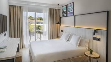 Una habitación de hotel con una cama grande, un escritorio y un balcón con cortinas.
