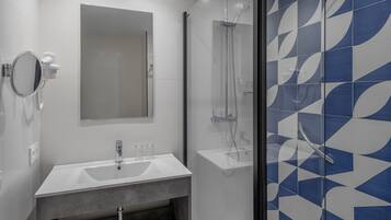 Un baño moderno con lavamanos, espejo y ducha blancos.