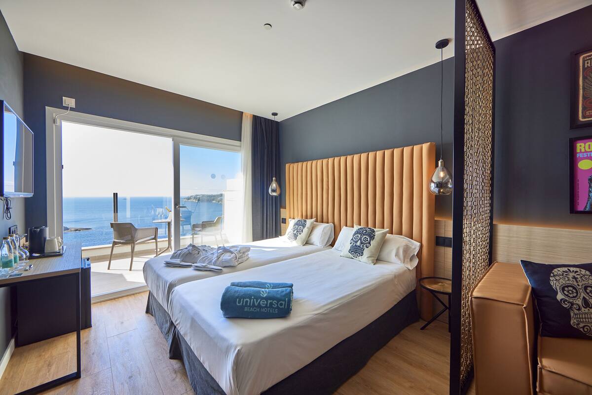 Une chambre d’hôtel moderne avec un grand lit, un bureau et une vue sur la mer.