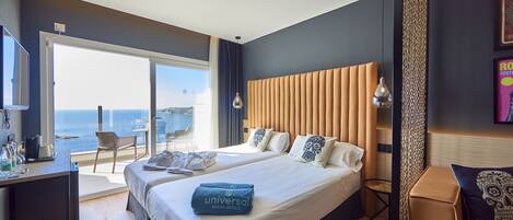 Habitación de hotel moderna con una cama grande, un escritorio y vista al mar.