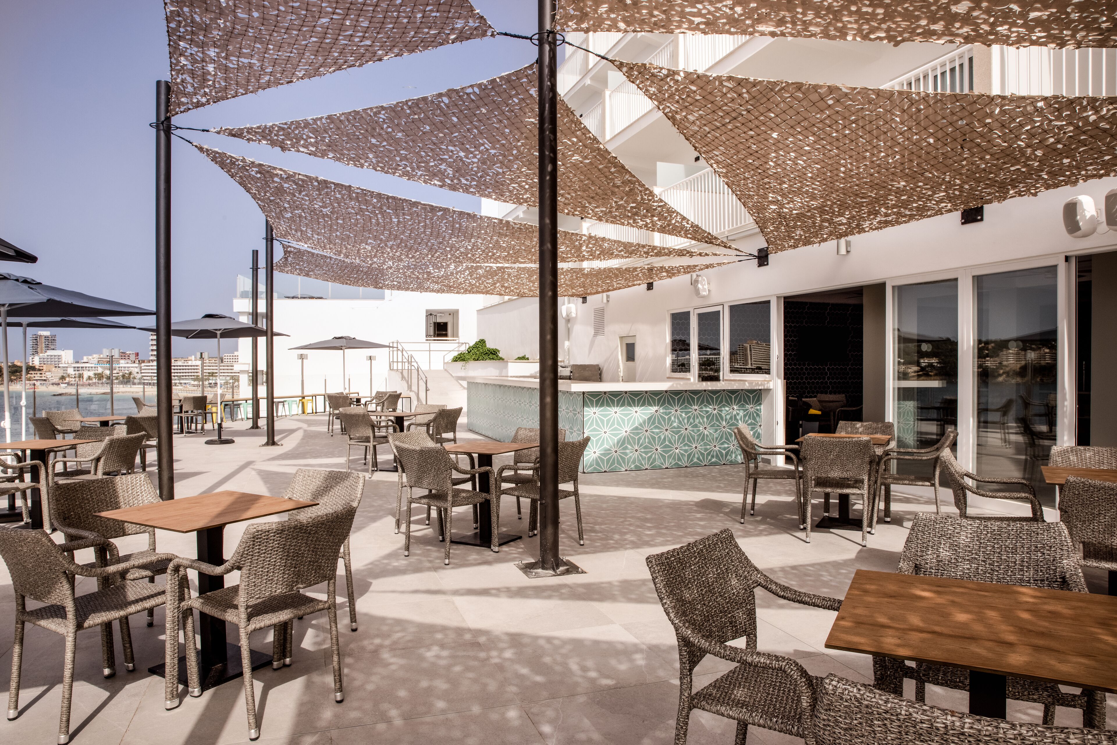 An outdoor seating area with wicker furniture and shaded by patterned umbrellas.