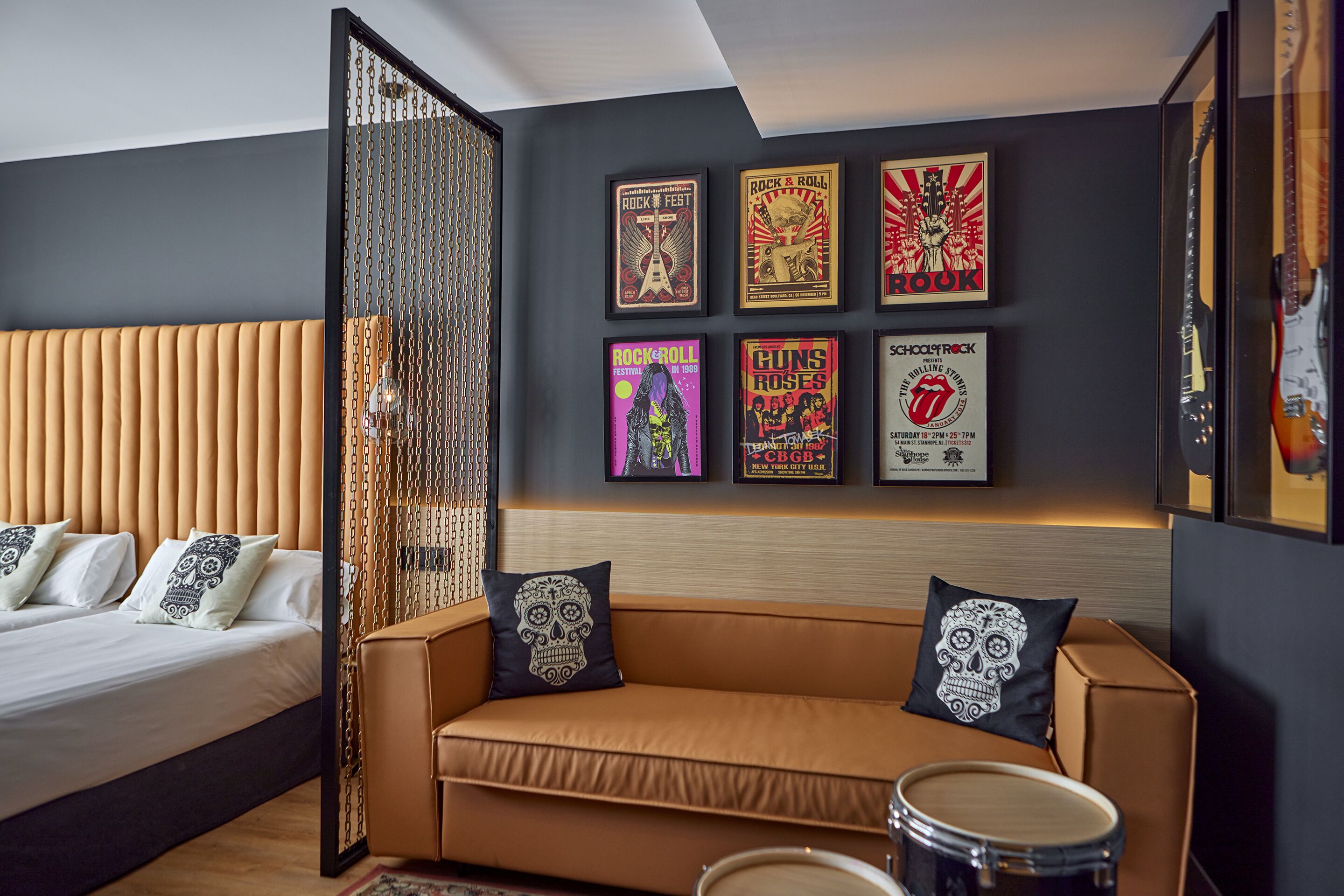 A modern hotel room with a bed, a sofa, and a wall adorned with framed posters.