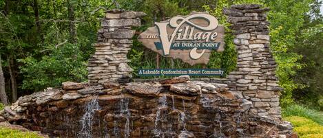 A sign for 'The Village at Indian Point' with a stone waterfall feature in front.