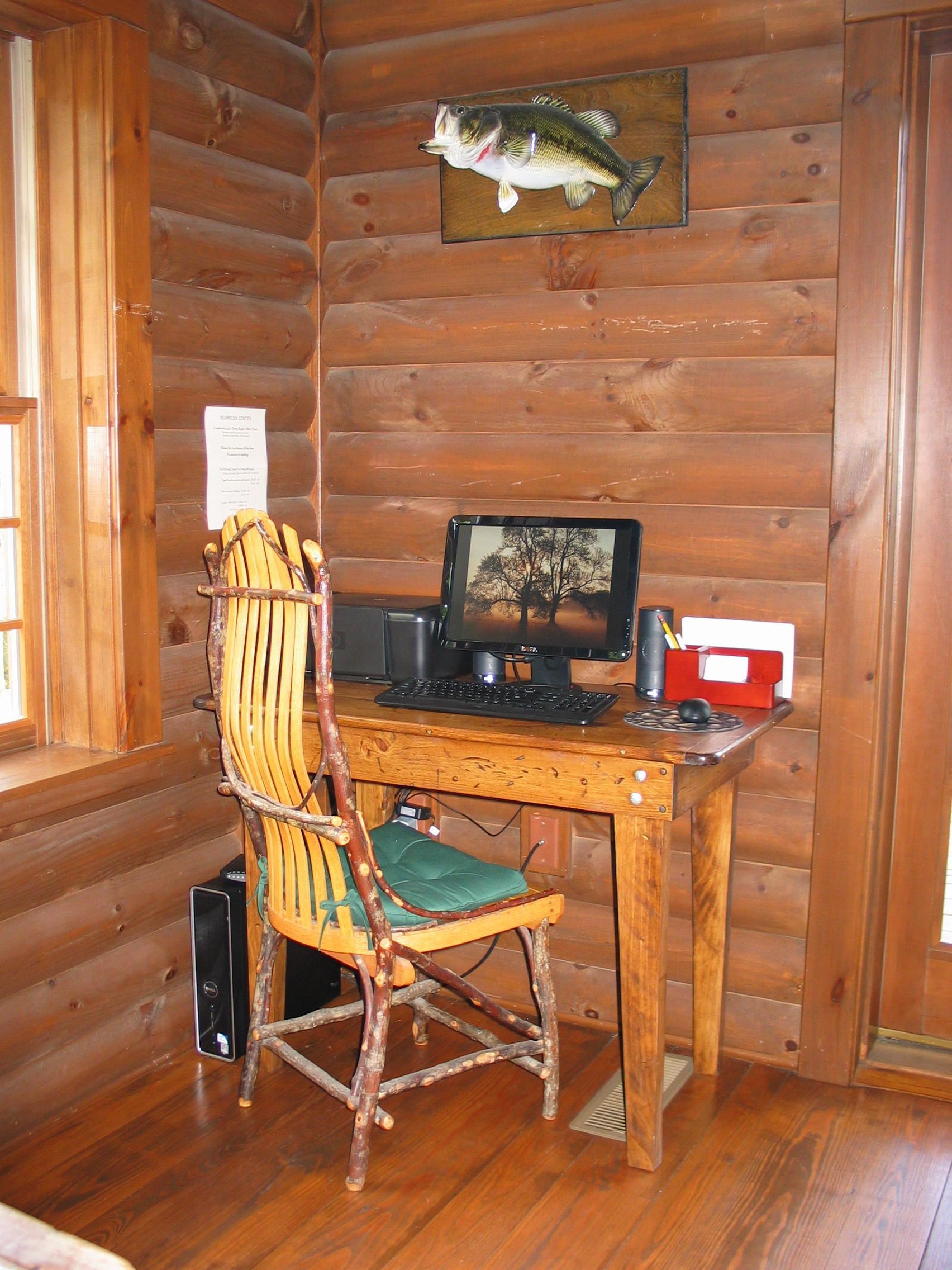 Interior d'una cabana de fusta amb una taula d'escriure, un ordinador i una cadira.