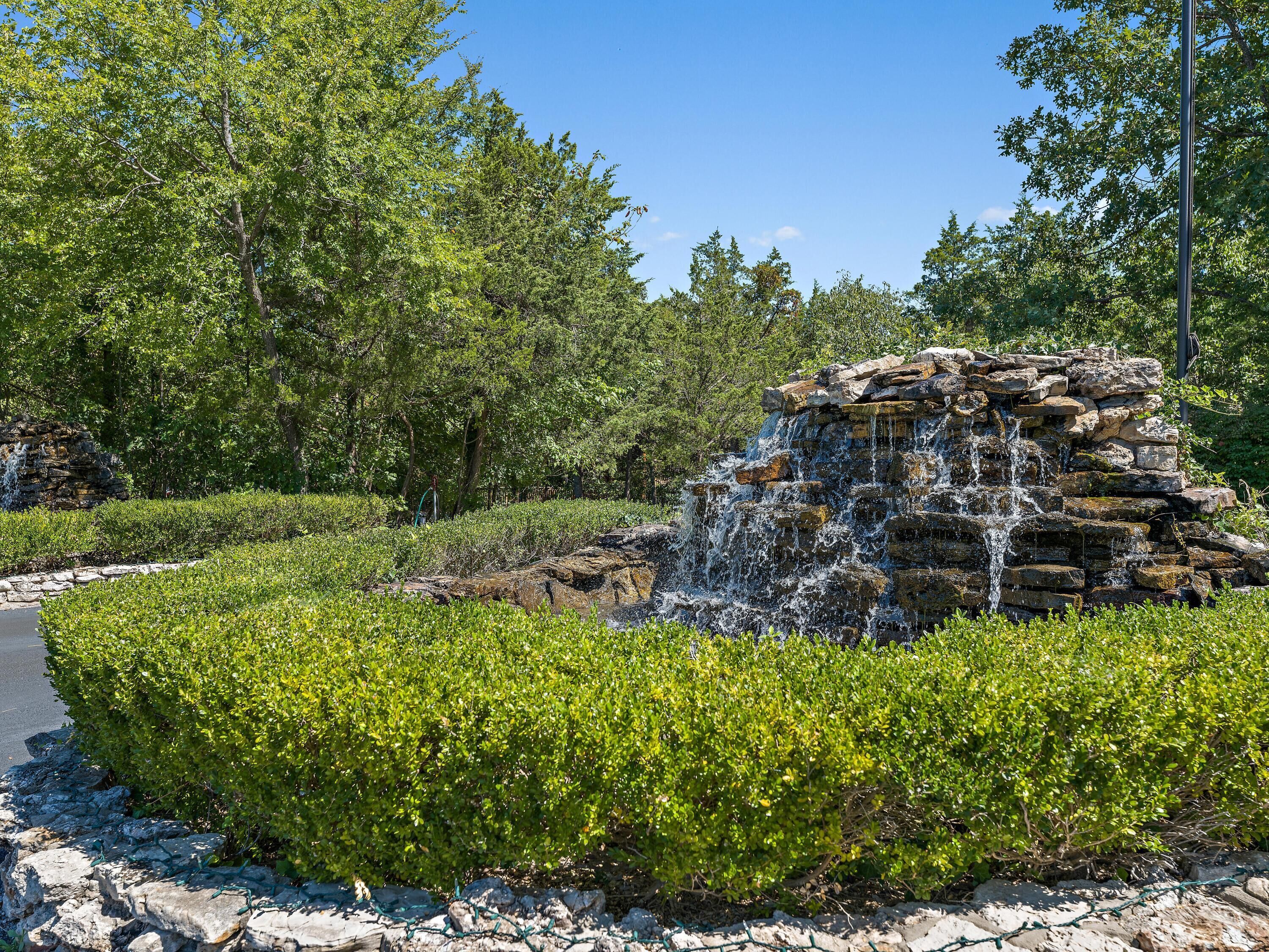 Un jardín ajardinado con una cascada rodeada de abundante vegetación y árboles.