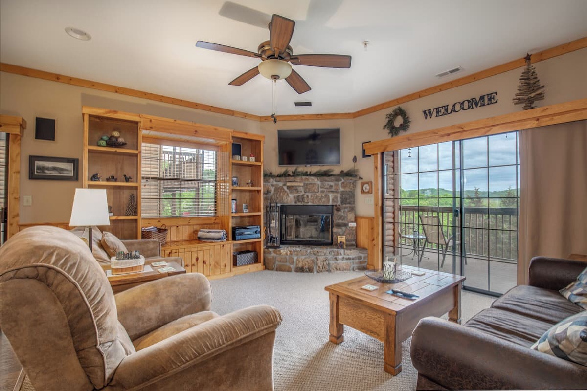 A cozy living room with a fireplace, wooden shelves, and a 'WELCOME' sign.