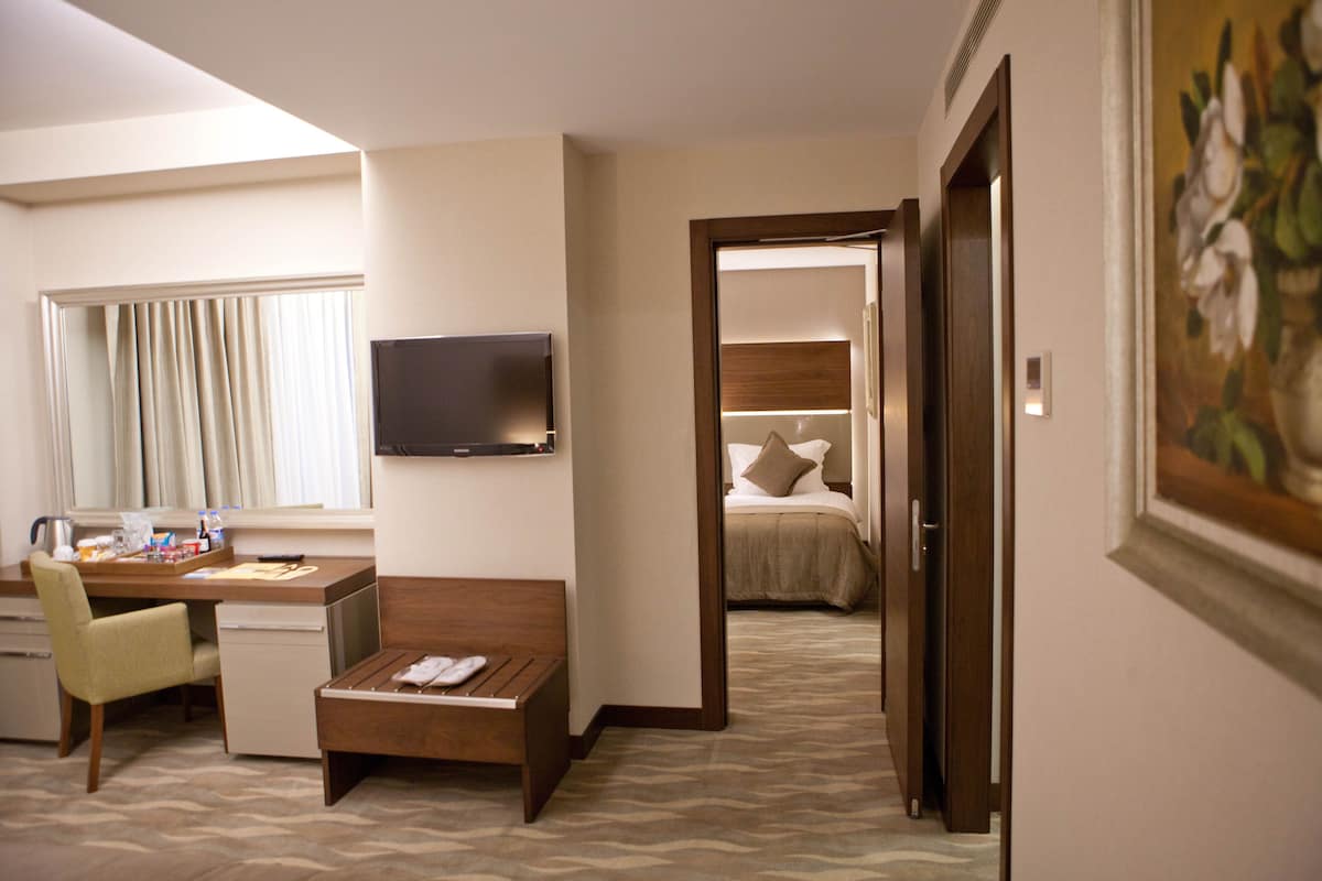 A hotel room with a desk, chair, and a bed with a headboard.