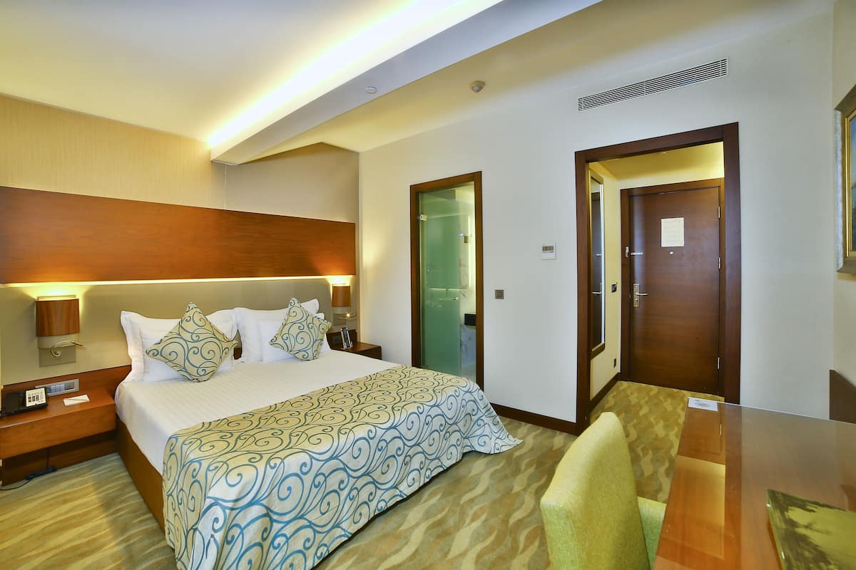 A hotel room with a large bed, bedside tables, a desk, and a chair.