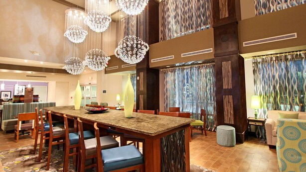 A spacious dining area with a long wooden table, multiple chairs, and hanging crystal chandeliers.