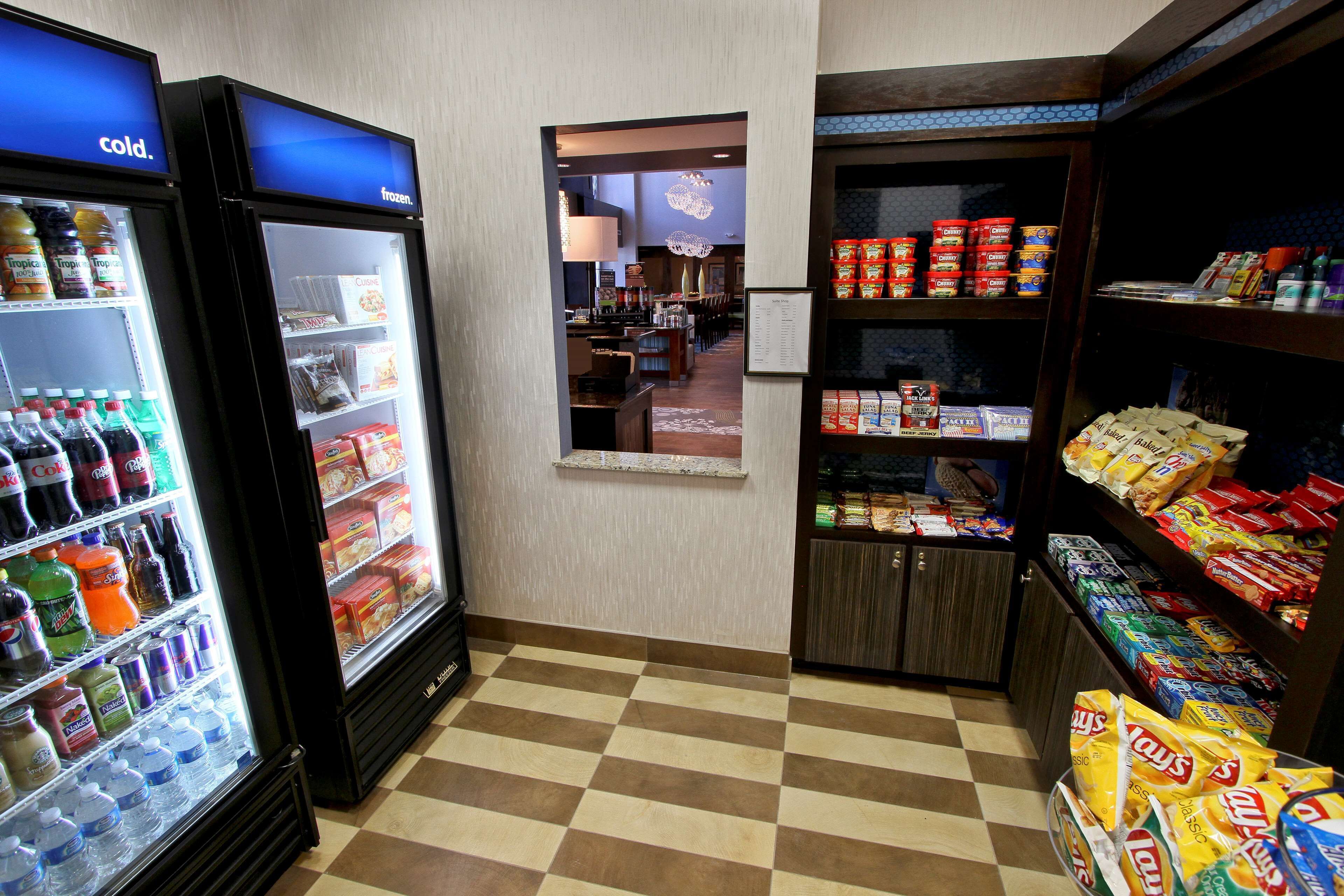 A small convenience store with a checkered floor, refrigerated beverage cases, and shelves stocked with snacks and beverages.