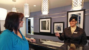 A reception area with framed pictures on the wall, a 'Welcome to Winnie' sign, and a counter with a name tag.