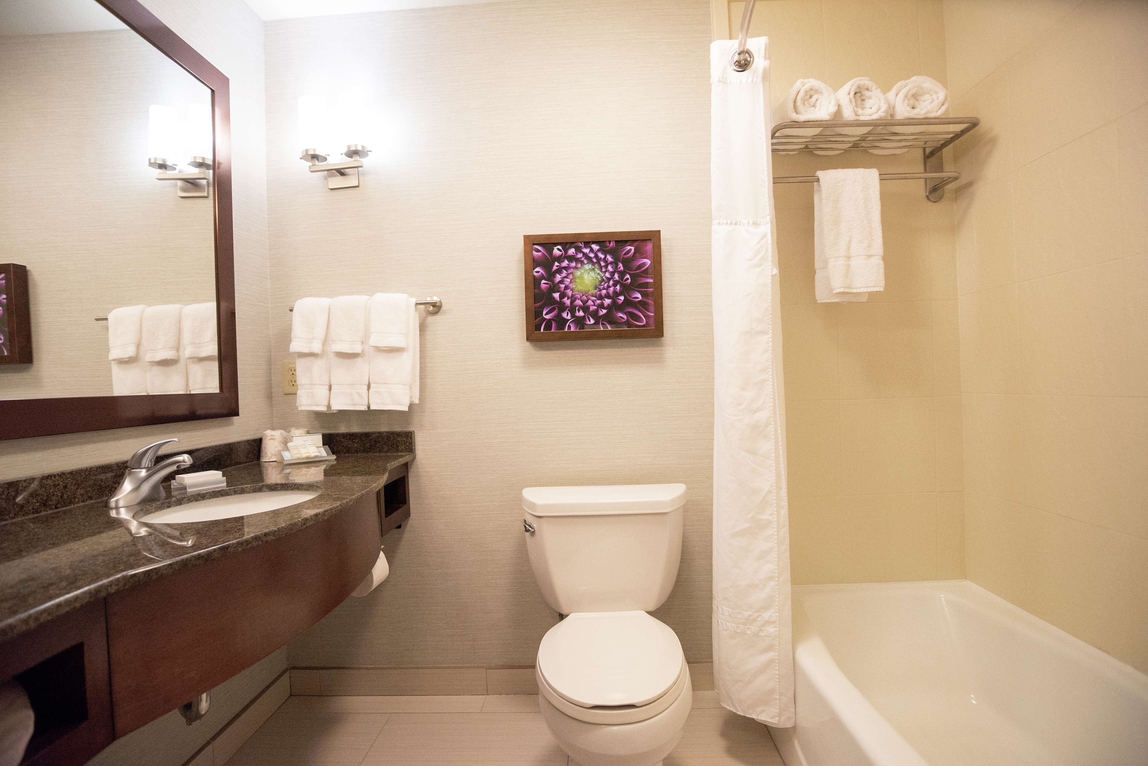 Une salle de bain avec un lavabo, des toilettes et une baignoire. Il y a des serviettes accrochées au mur et un rideau de douche.