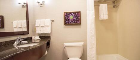 Une salle de bain avec un lavabo, des toilettes et une baignoire. Il y a des serviettes accrochées au mur et un rideau de douche.