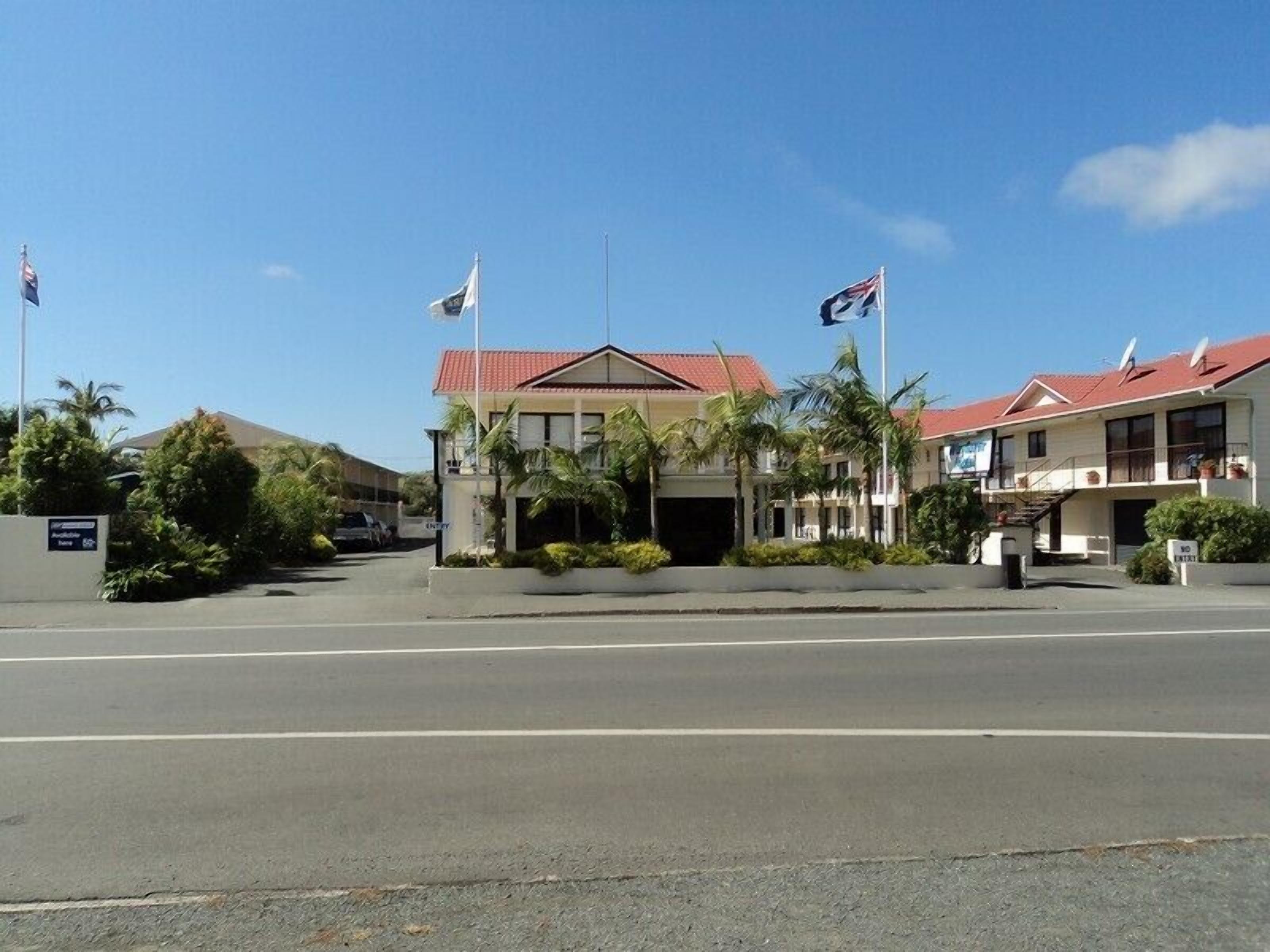 A hotel with a red roof, multiple flags, and a clear sky.
