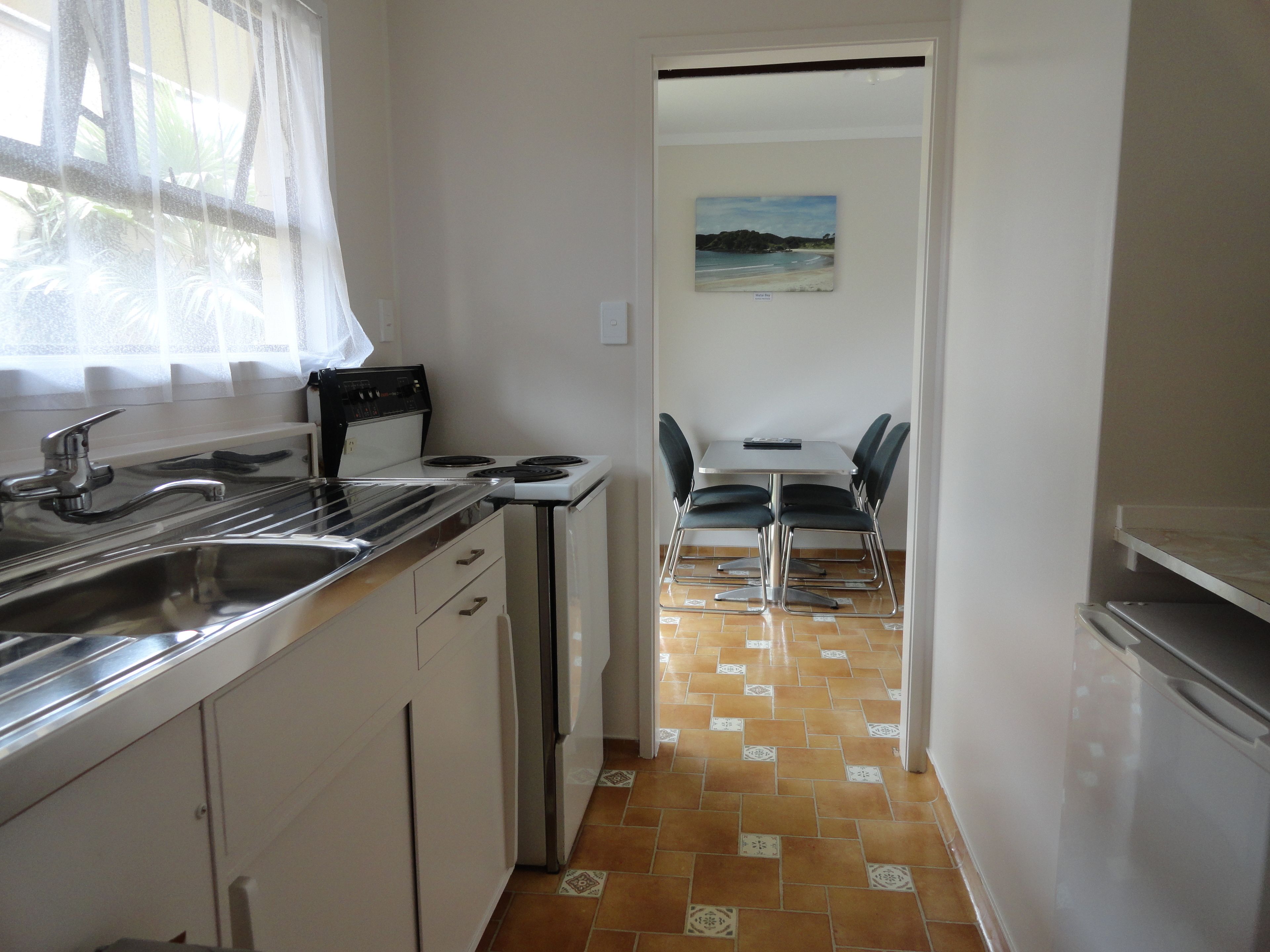 A compact kitchen with a stove, sink, and dining area with chairs.