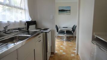 A compact kitchen with a stove, sink, and dining area with chairs.