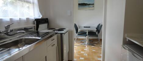A compact kitchen with a stove, sink, and dining area with chairs.