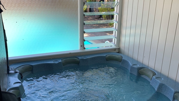 A hot tub with a view of a garden through a window.