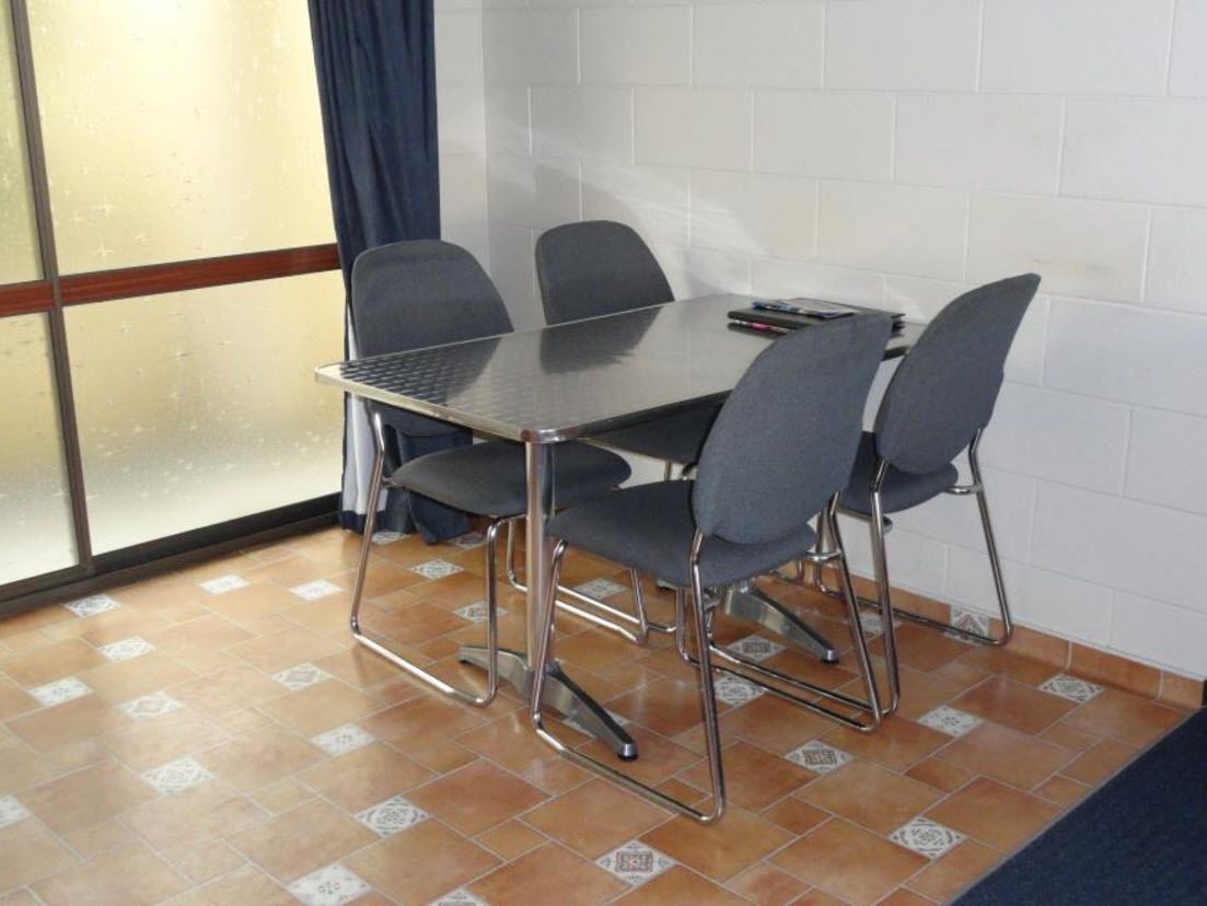 A conference room with a glass partition, a tiled floor, and a blue curtain.