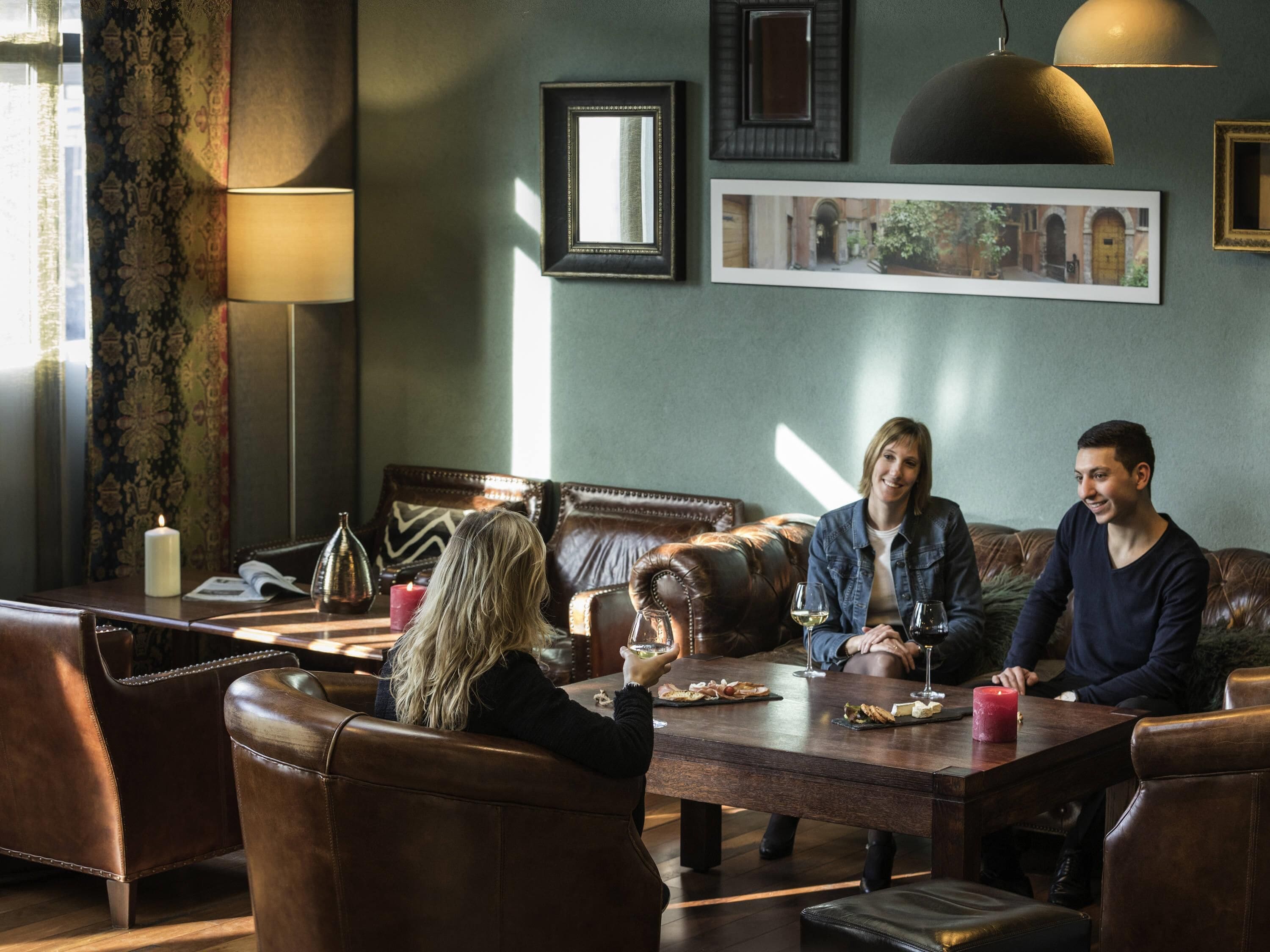 Un coin repas avec des meubles en cuir, une table avec des verres à vin et des tableaux encadrés au mur.