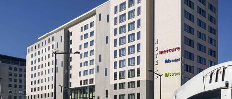A modern hotel building with multiple floors, large windows, and a prominent sign for 'Mercure' on the side.