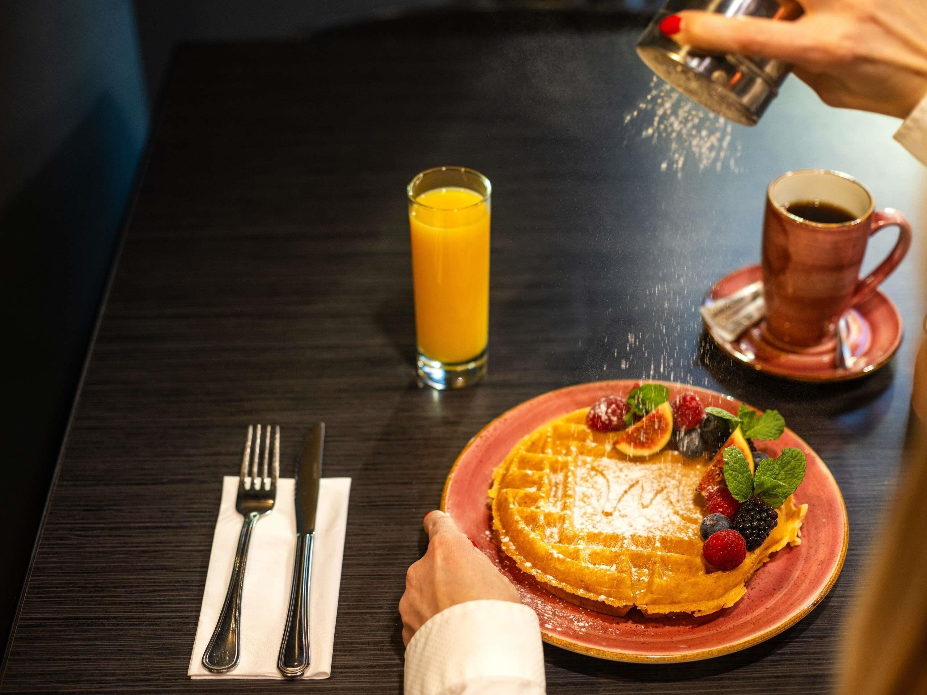 A breakfast setting with a plate of food, a glass of orange juice, and a cup of coffee on a table.