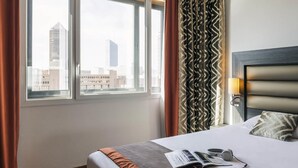 A hotel room with a bed, a window with curtains, a headboard, and a lamp. - Hôtel Mercure Lyon Centre - Gare Part Dieu (Lyon)