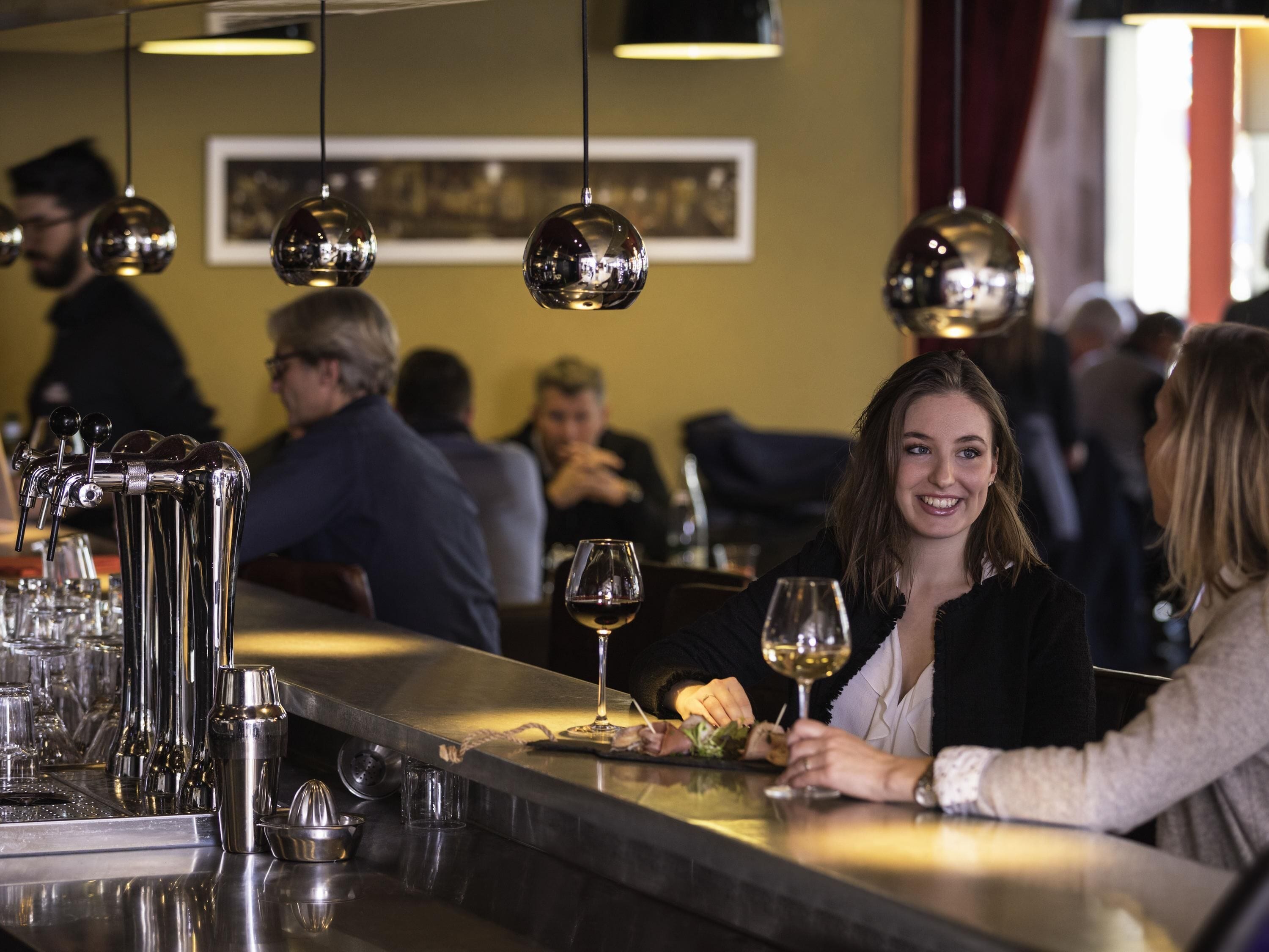 Un espace bar doté d’un comptoir élégant, de divers ustensiles de bar et de luminaires sphériques suspendus.