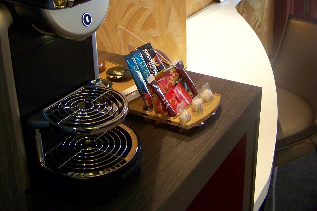 A coffee machine with a tray of snacks and a television mounted on the wall.