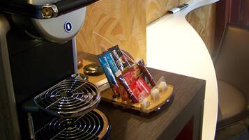 A coffee machine with a tray of snacks and a television mounted on the wall.